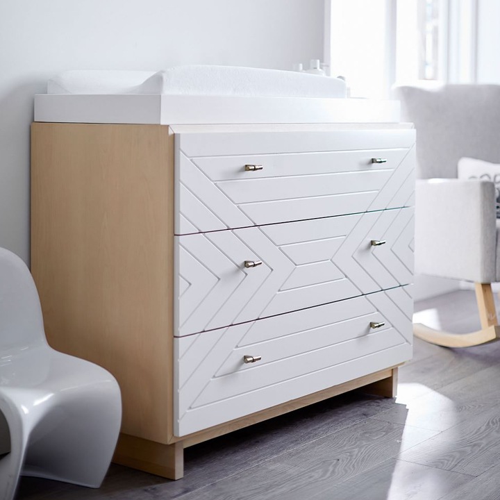 Three-drawer changing table with geometric front.