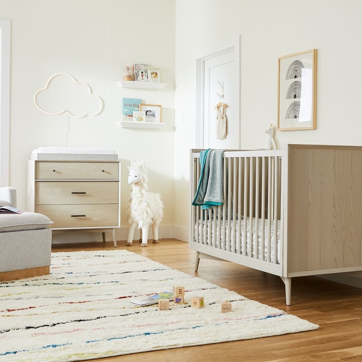 White nursery with colorfully striped rug.