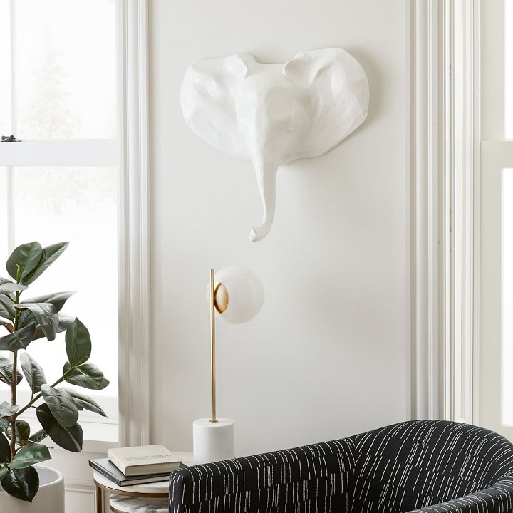 White papier-mache elephant head on white wall.