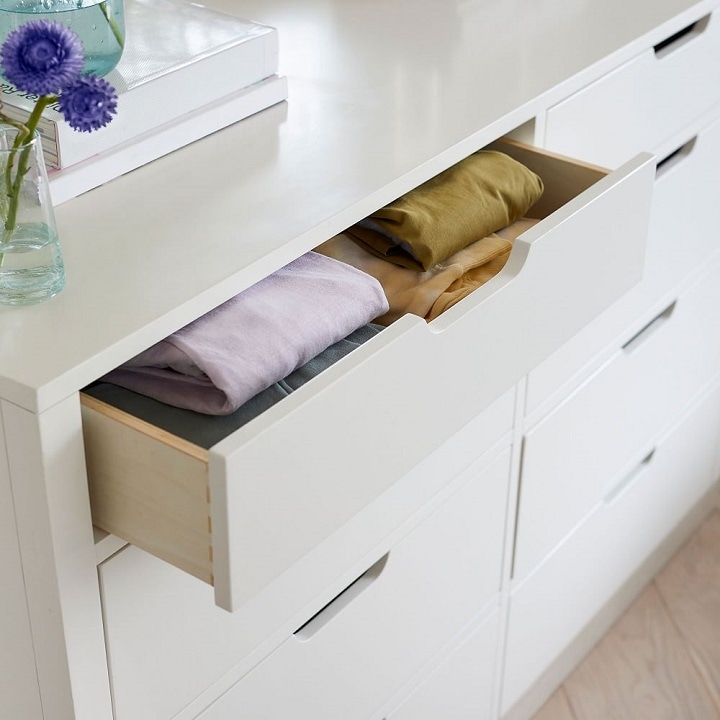 White dresser with open drawer and folded clothes.