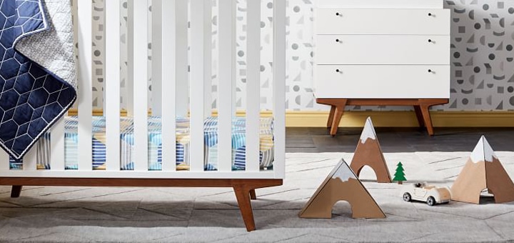Crib in child’s nursery with toys and other furniture