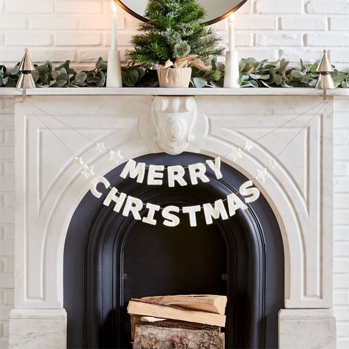 merry christmas banner hanging on white fireplace