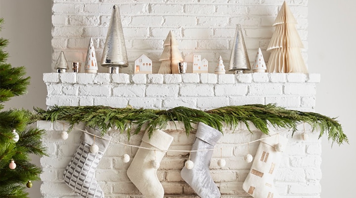 four stockings on brick fireplace with christmas decor