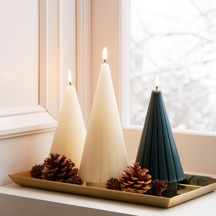 christmas tree shaped candles lit on gold tray
