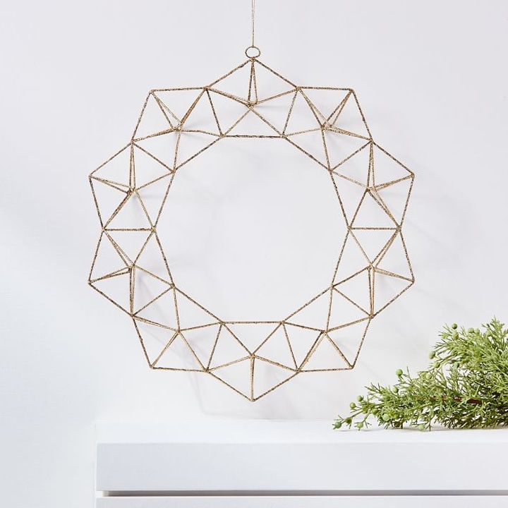 geometric wire wreath hanging on white wall