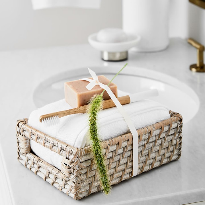 woven basket with towel, wooden toothbrush and soap bar