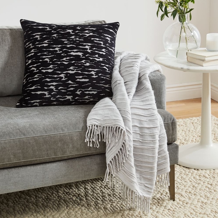 Textured throw blanket draped over modern gray sofa
