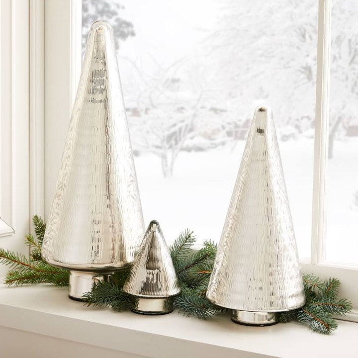 three silver christmas tree figures on window sill