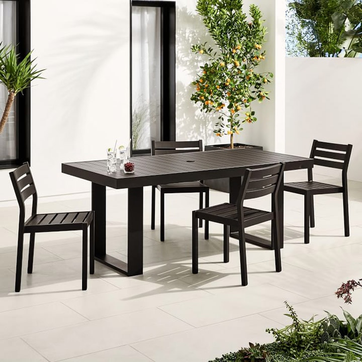 Modern black outdoor dining set with plants.