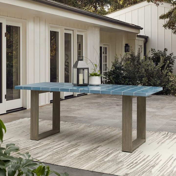 Outdoor dining table with blue stripes and rug.