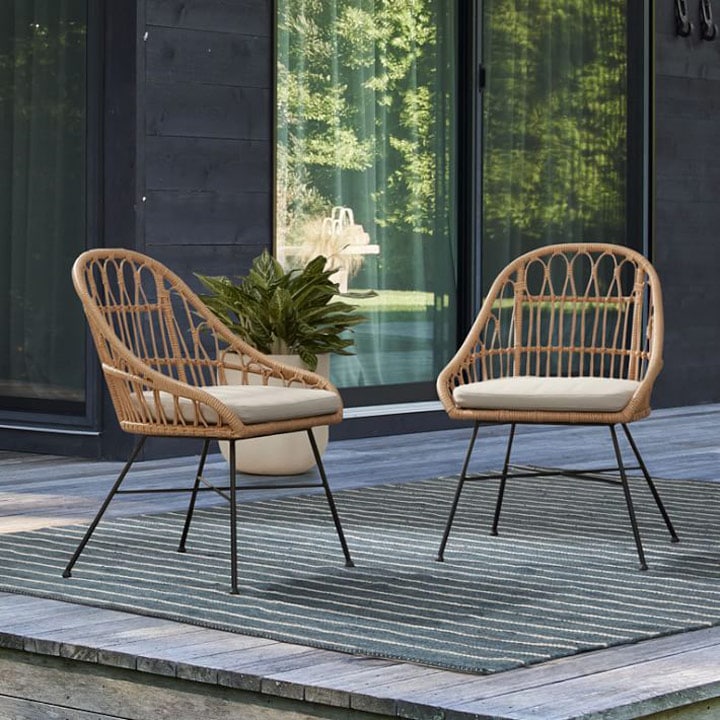 Two outdoor chairs with cushions and striped rug.