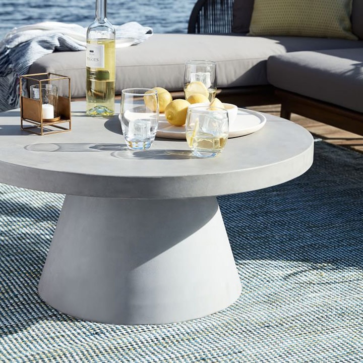 Round concrete table with wine glasses and lemons. 