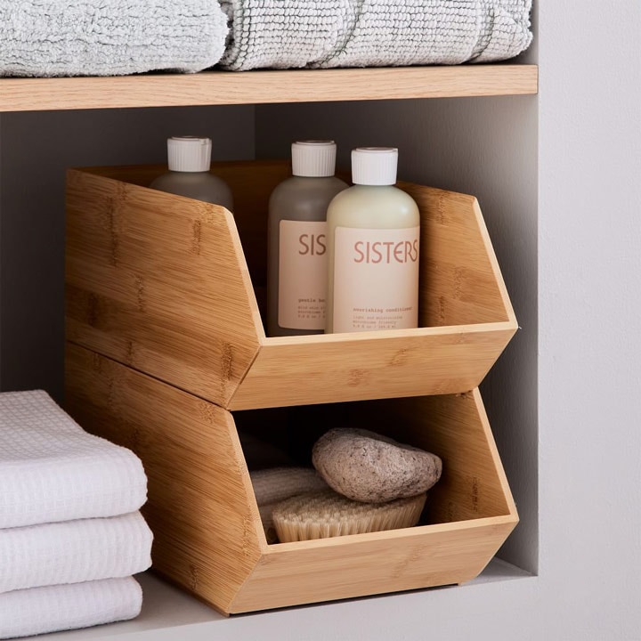 Stacked wooden storage bins with bath products and towels.