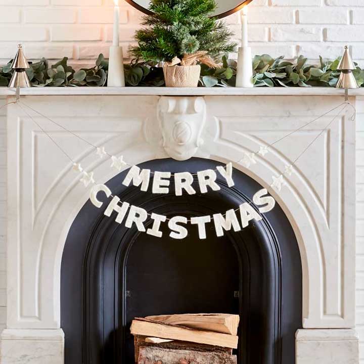 merry christmas banner hanging on white fireplace