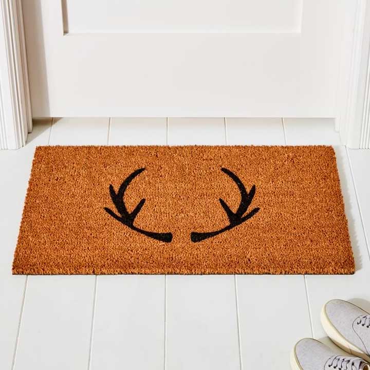 brown welcome mat with antlers on white floor
