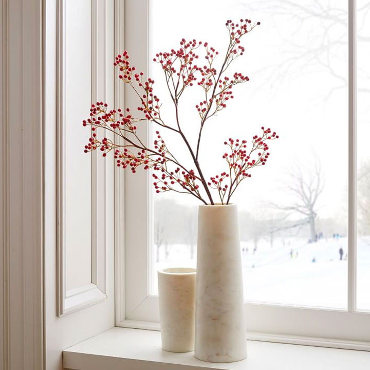 branch with red berries in stone vase near window