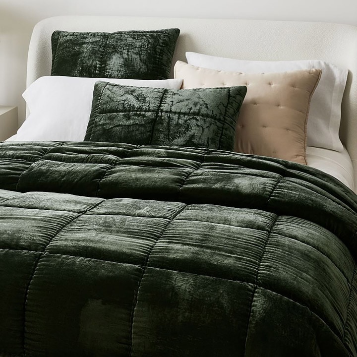bed with dark green comforter and pillows