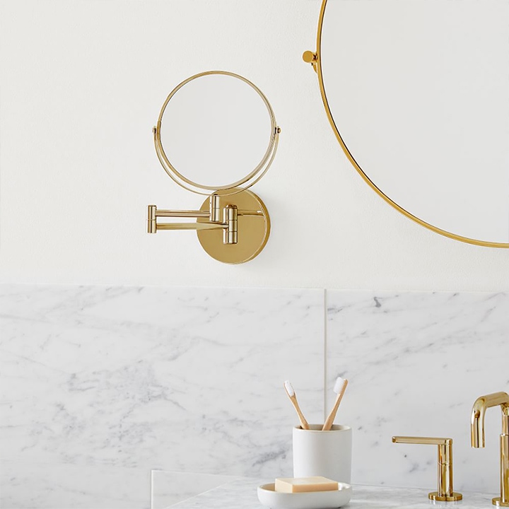 Mounted brass swivel mirror above bathroom counter.