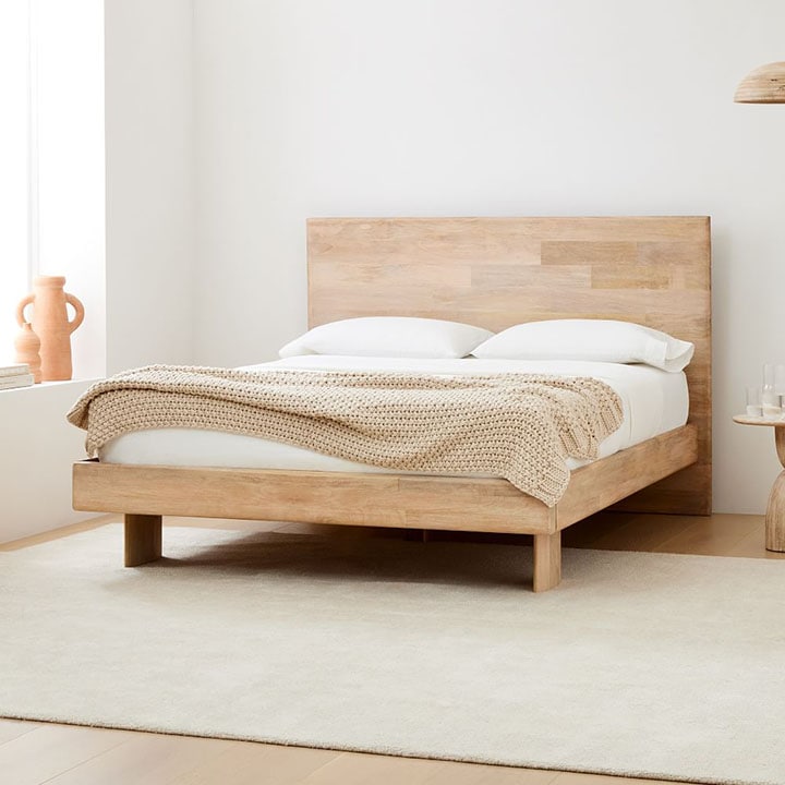 Solid wood bed frame in neutral-toned bedroom.
