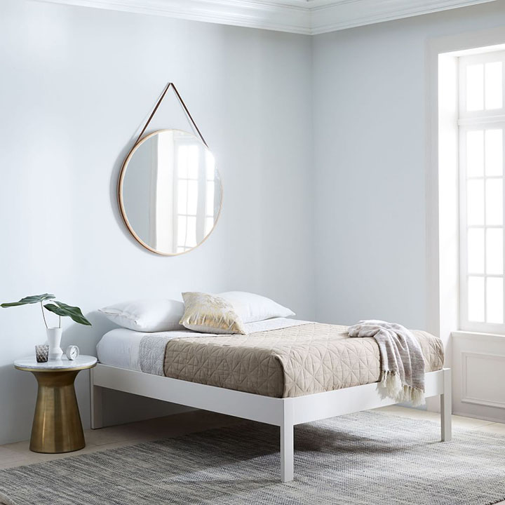 Large circular mirror hanging above a bed.