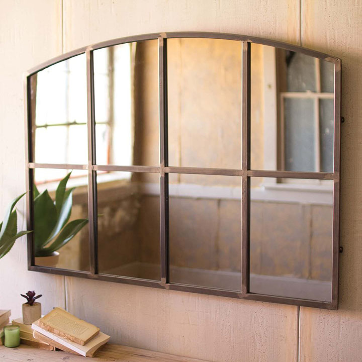 Arched metal wall mirror hanging on a wall.