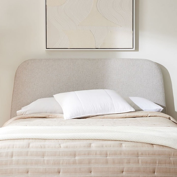 Neutral rounded-edged headboard in bedroom.