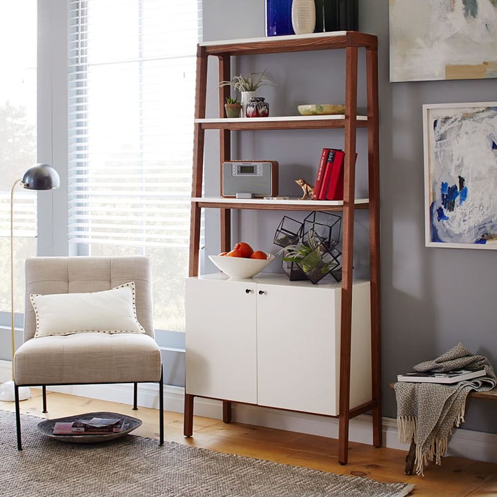 White accent chair with white pillow next to white and wood ladder bookcase in reading nook. White accent chair with white pillow next to white and wood ladder bookcase in reading nook.