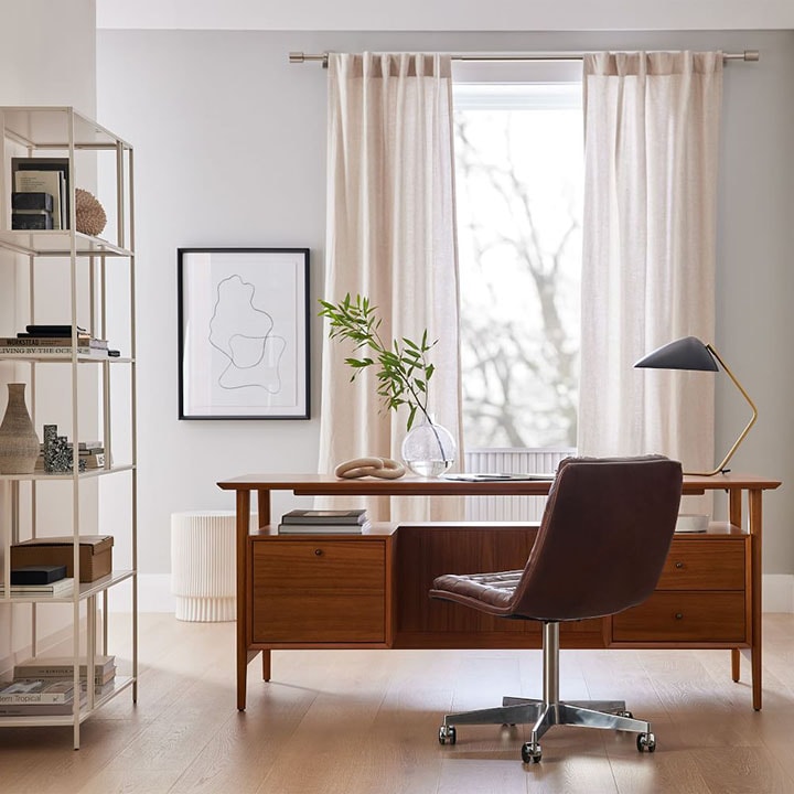 Home office with dark wood desk, brown leather desk chair, white curtains, and white bookcase. Home office with dark wood desk, brown leather desk chair, white curtains, and white bookcase.