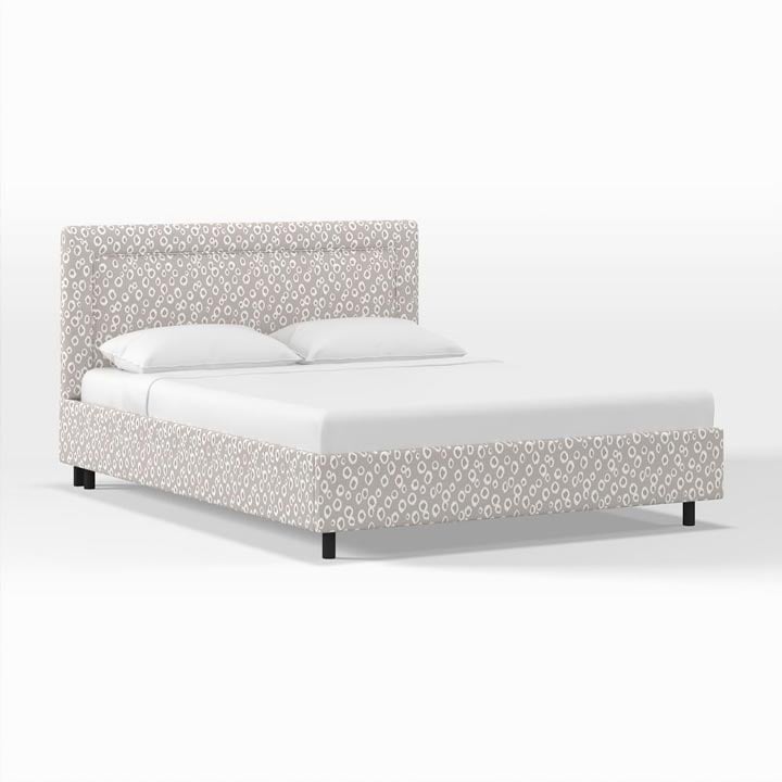 Leopard spot patterned Upholstered Bordered Platform Bed styled with white bedding. 