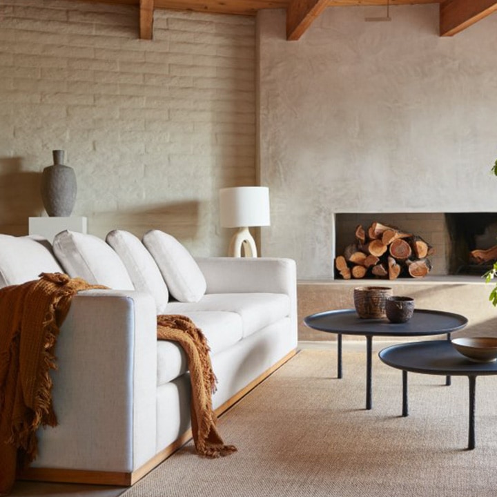 White sofa, beige rug and natural wood accent furniture. White sofa, beige rug and natural wood accent furniture.