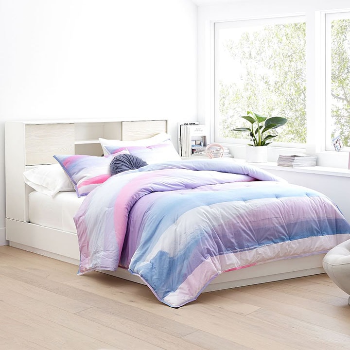 White storage headboard with pink and purple watercolor bedding.