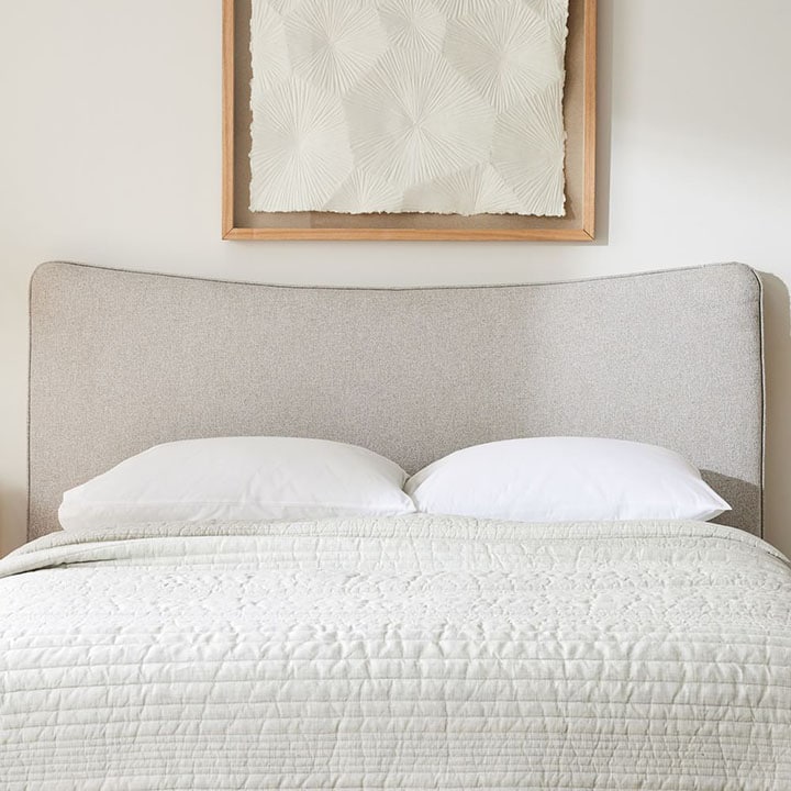 Neutral swooping modern headboard in bedroom.