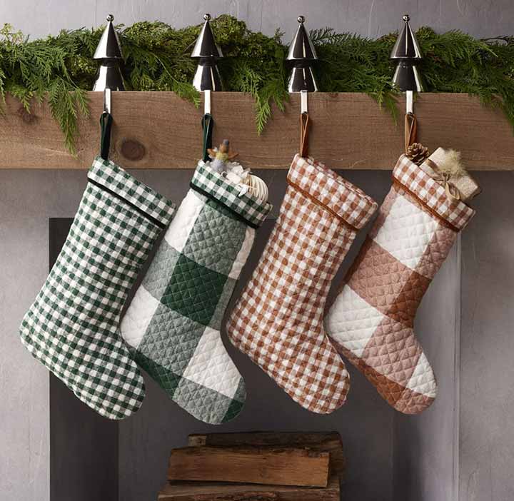 Set of four modern Christmas stockings in buffalo check and natural linen hanging from a mantel