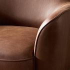 Curved arm of the brown leather chair with visible stitching and leather texture.