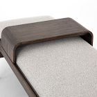 Close-up of the curved wooden tray-like headboard/footboard crossover over a light textile