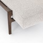Edge of a daybed showing the joint between wooden leg and light upholstery fabric