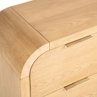 Close-up of curved corner and integrated handle on light wood dresser