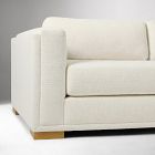Close-up of the arm and pillow edge of a light beige sofa.