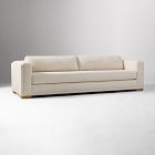Long cream sofa with wooden block feet and cushions, studio shot.