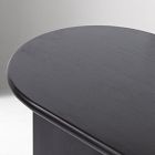 Curved edge of an oval coffee table with a dark finish.