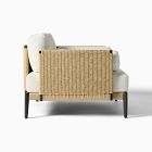 Rear view of wicker armchair with light woven rattan and white cushion