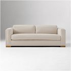 Beige sofa with three cushions and wooden feet in a studio.